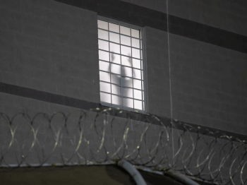 Detention facility with shadow figure in window